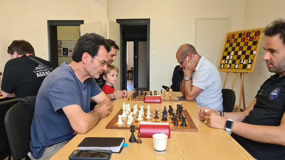 Adhésion au club l'échiquier Agenais, on voit une table sur laquelle des joueurs s'affrontes aux échecs. Gros moment de concentration.